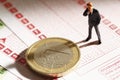 Manager figurine standing on betting slip with euro coin, close up Royalty Free Stock Photo