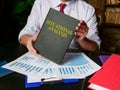 Man holds situational analysis report and pile of charts.