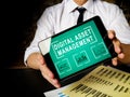Manager holds tablet with Digital asset management data.