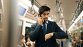 Manager look at watch while standing in train with blurred background. Exultant. Royalty Free Stock Photo
