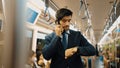 Manager look at watch while standing in train with blurred background. Exultant. Royalty Free Stock Photo