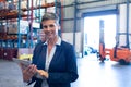 Manager looking at camera while using digital tablet in warehouse Royalty Free Stock Photo