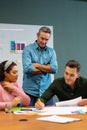 Manager looking at multiracial colleagues discussing business strategy in meeting at creative office Royalty Free Stock Photo