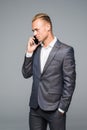 Manager, man or businessman talking on smartphone or mobile phone in stylish suit on grey background. Technology for business.