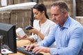 Manager scanning box while her colleague typing on laptop