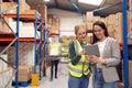 Manager Using Digital Tablet With Female Intern Inside Busy Warehouse Facility Royalty Free Stock Photo