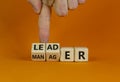 Manager versus leader symbol. Businessman flips wooden cubes and changes the word `manager` to `leader`. Beautiful orange Royalty Free Stock Photo