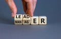Manager versus leader symbol. Businessman flips wooden cubes and changes the word `manager` to `leader`. Beautiful grey backgr Royalty Free Stock Photo