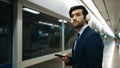 Manager wearing headphone at train station while holding mobile phone. Exultant. Royalty Free Stock Photo