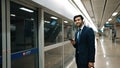 Manager wearing headphone at train station while holding mobile phone. Exultant. Royalty Free Stock Photo