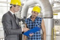 Manager with worker discussing over clipboard in industry Royalty Free Stock Photo