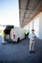 Manager working on tablet and warehouse workers loading the cardboard boxes