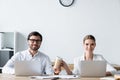 managers working with laptops together and passing paper cup of coffee