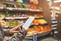 Managing her shopping with a mobile app. a woman using a mobile phone in a grocery store. Royalty Free Stock Photo