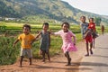 Manandoana, Madagascar - April 26, 2019: Group of unknown Malagasy kids running on road next to rice field, small hills in