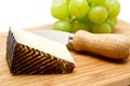 Manchego cheese ang grapes on chopping board Royalty Free Stock Photo