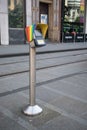 Ticket purchase validation point machine on metal pole on pavement for public transport. Pride rainbow symbol on top