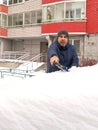 A mancleans snow from his car parked in a residential area