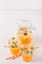 Mandarin cocktail with ice and mint in beautiful glasses and jug, fresh ripe citrus on white wooden background. Sweet orange juice Royalty Free Stock Photo