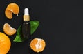 Mandarin essential oil citrus in a glass bottle on a leaf of tangerine tree. Black stone background. Next to a bottle of oil are Royalty Free Stock Photo