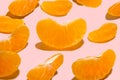 Mandarin slices on a pink background with shadow, pattern. A set of ripe mandarin slices. Close-up photo of a piece of tangerine. Royalty Free Stock Photo