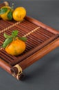 Mandarine fruite with leaves on a bamboo tray on a grey background