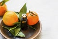 Mandarines essential oil bottle, aromatherapy citrus oil with mandarine fruits in wooden plate