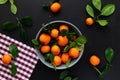 Mandarins or clementines with leaves on a black background. Tangerines in a plate Top view. Royalty Free Stock Photo