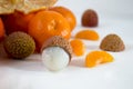 Mandarins on a white background with lobule, peel, citron and litchi. Side view, close. Citrus reticulata. Litchi chinensis