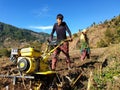 A young Indian boy driving mini tractor for wheat cultivation in terraced field, Land cultivation with rototiller.