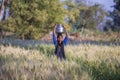 Indian girl with a jug with water on her head goes through a wheat field in Indian village Mandu, India