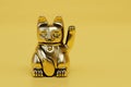 Maneki Neko isolated on yellow background. Japanese lucky cat, figurine golden cat brings good luck. 3d render Royalty Free Stock Photo