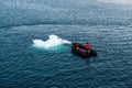 Maneuvering orange lifeboat in water in Arctic waters, Svalbard. Abandon ship drill. Lifeboat training. Man over board drill