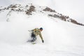 Manful snowboarder riding down the slope in the mountain resort