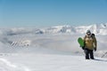 Manful snowboarder walking with the snowboard on the background