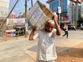 An elderly Indian labourer transporting a heavy wooden box on his shoulders Royalty Free Stock Photo