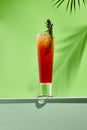 Mango and berries lemonades drink on white table. Green wall in sunlight with palm leaf hard shadow. Summer, tropic, fresh drink