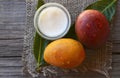 Mango body butter in a glass bowl and fresh ripe mangoes fruit on old wooden table. Royalty Free Stock Photo