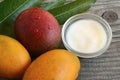 Mango body butter in a glass bowl and fresh ripe organic mango fruits on old wooden background.Spa,natural oils,organic cosmetic o Royalty Free Stock Photo