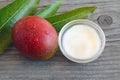 Mango body butter in a glass bowl and fresh ripe organic mango fruit on old wooden background.Spa,natural oils,organic cosmetic o Royalty Free Stock Photo