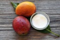 Mango body butter in a glass bowl and fresh ripe organic mango fruits on old wooden background.Spa,natural oils,organic cosmetic o Royalty Free Stock Photo