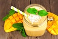 Mango coconut smoothie in a jar, close up over wood