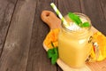 Mango coconut smoothie in a mason jar on a paddle board