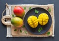 Mango cut in half and cubed on a wooden board, two whole mango. Top view