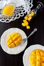 Mango fruit cubes and mango juice puree on dark wooden background.