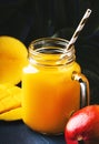 Mango juice or cocktail in glass jar with fresh fruit on blue tropical background, copy space, selective focus Royalty Free Stock Photo