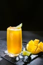 Mango juice on a dark background. Summer drink with ice and slices of mango and lime. Royalty Free Stock Photo