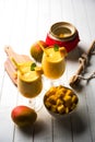 Mango Lassi or smoothie in big glass or small bottles with curd, cut fruit pieces and blender. Royalty Free Stock Photo