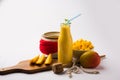 Mango Lassi or smoothie in big glass or small bottles with curd, cut fruit pieces and blender. Royalty Free Stock Photo