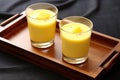 mango lassi in a transparent cup on a wooden coaster